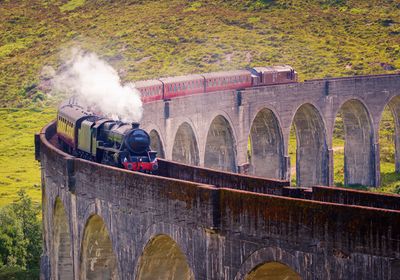 A steam train going over a viaduct.