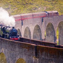 A steam train going over a viaduct.