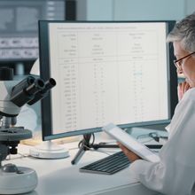 <p data-pm-slice="1 1 []" >Scientists working at a lab bench analyzing research data, with a computer screen and microscope in the foreground.</p>