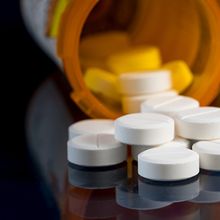 Oxycodone pill bottles on a table with one of the bottles tipped over and overflowing.&nbsp;