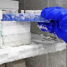 A researcher removes a tube rack from an ultra-low temperature freezer with frost build-up.