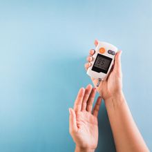 hands of a person checking their blood glucose level with a monitor