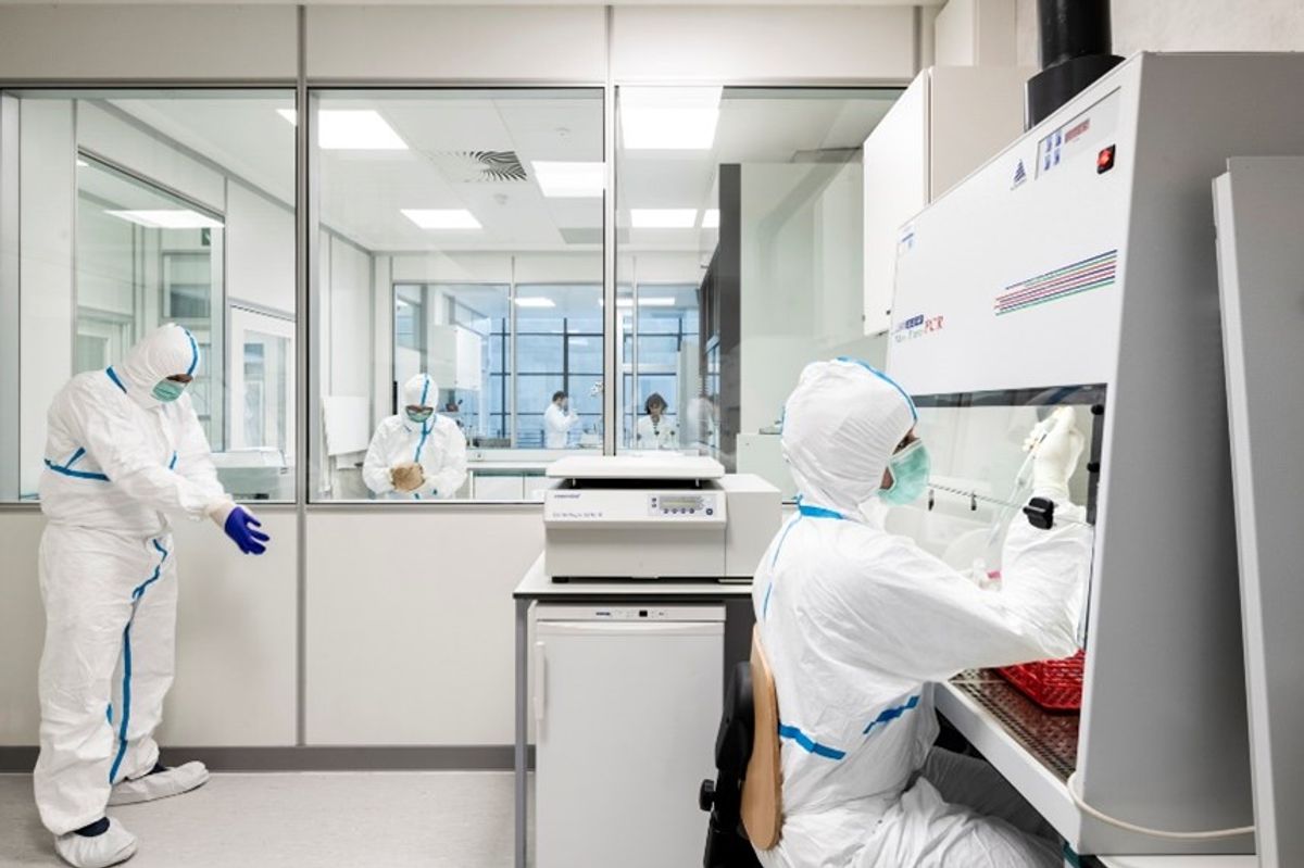 Researchers dressed in white biohazard gear conducting research in a laboratory.