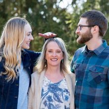 a smiling woman standing between a much taller man and woman