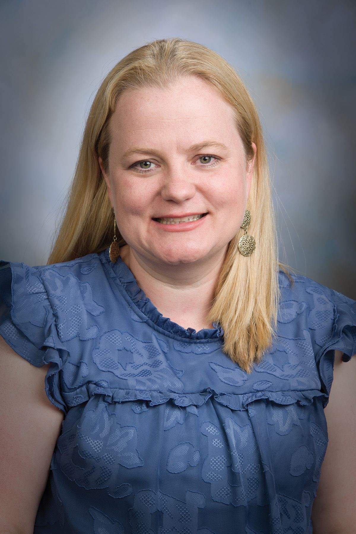 Julie Moreno wears a blue shirt against a grey background.