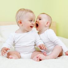 Two babies engaged in conversation, with one shouting in the other&rsquo;s ear