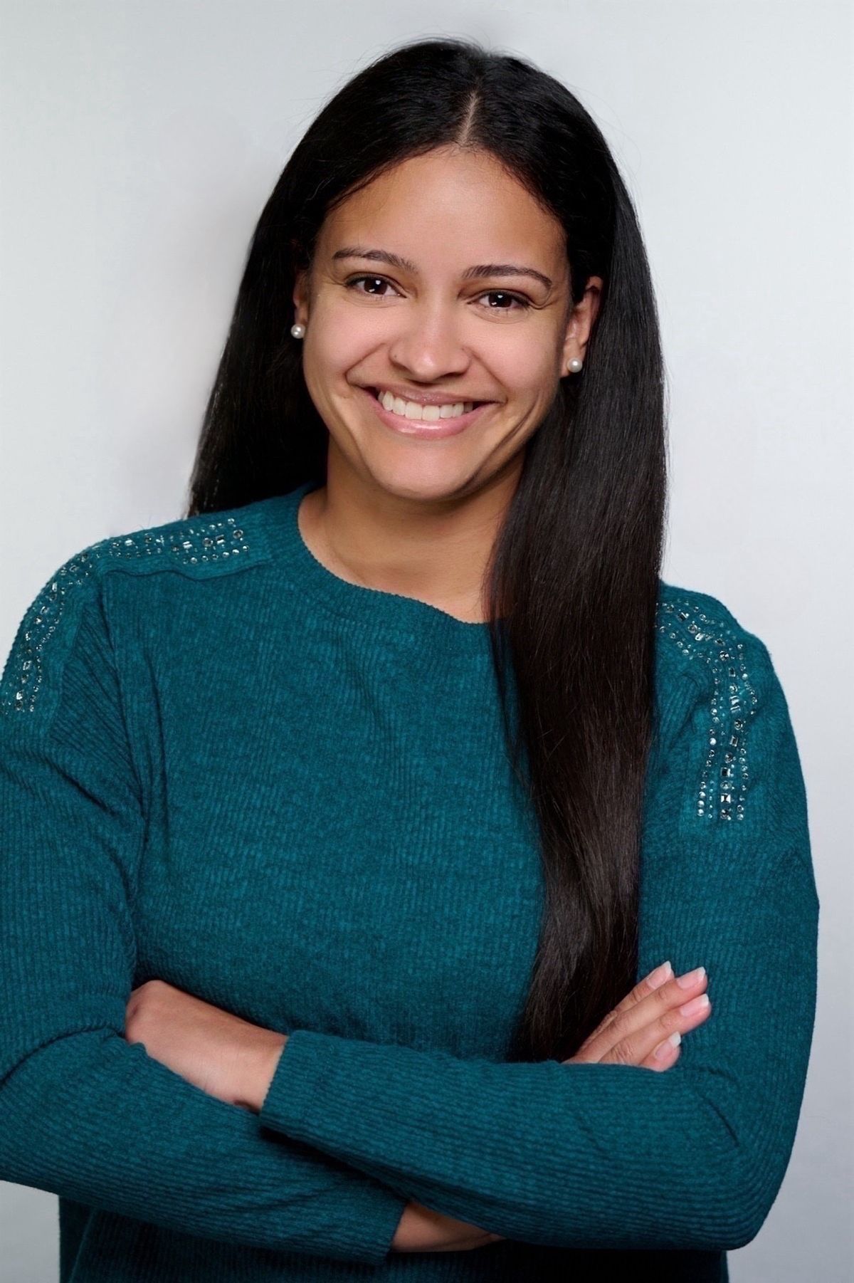 A photograph of Nathalie Fuentes. She has dark hair and is wearing a long-sleeved turquoise shirt, smiling at the camera.