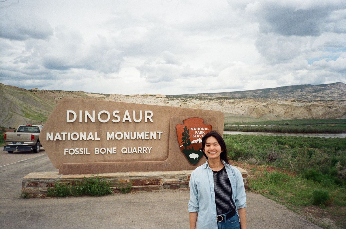 Film photo of Laura standing in front of a sign at the Dinosaur National Monument.