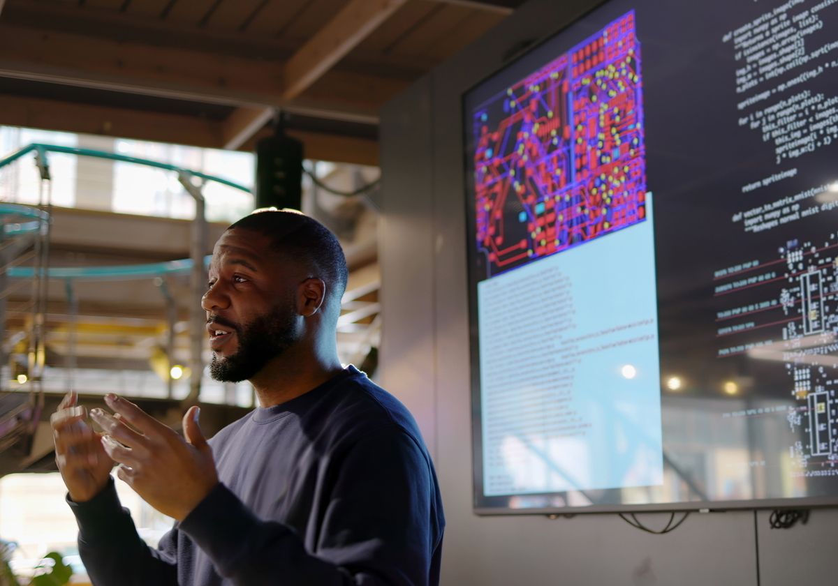 An individual standing in front of a screen, delivering a lesson.