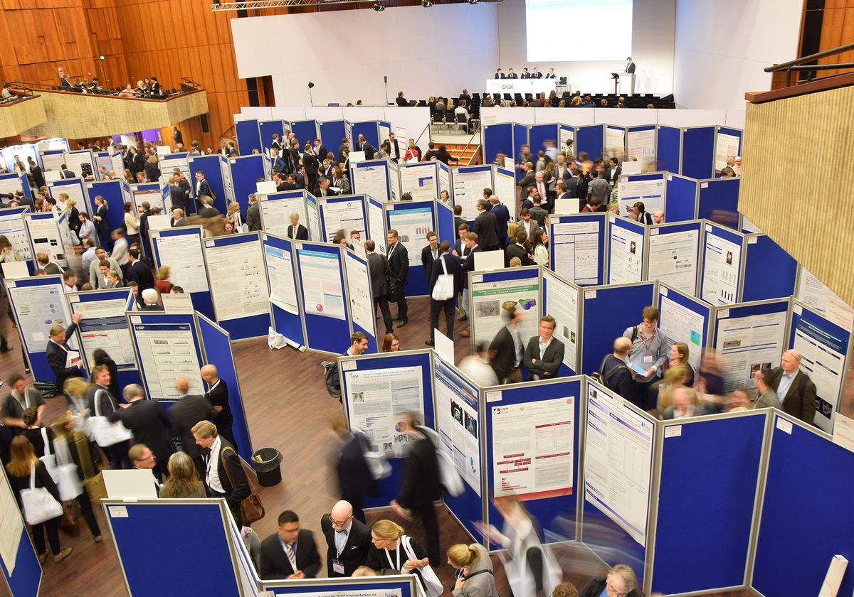 An overhead shot of a busy conference hall filled with posters and presenters.