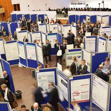 An overhead shot of a busy conference hall filled with posters and presenters.