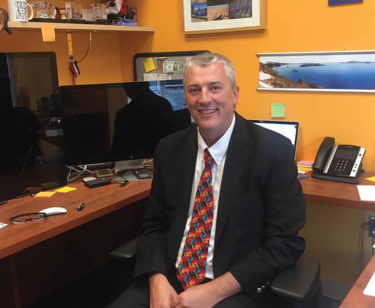 Mario Roederer, an immunologist at the National Institute of Allergy and Infectious Disease, sits at his computer desk in a black suit with a red and blue patterned tie.