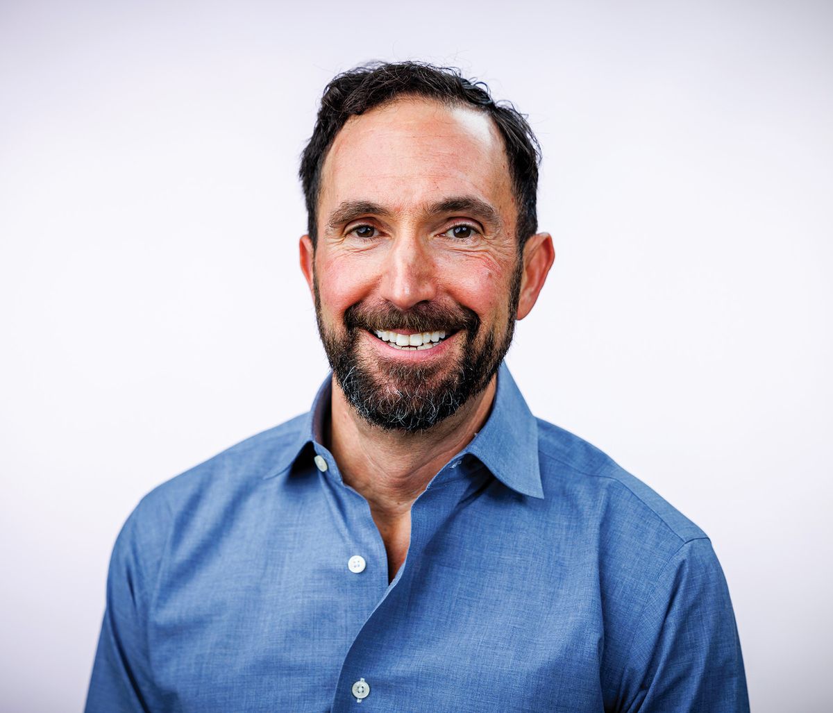 Photograph of Stephen De Rosa, an immunologist at the University of Washington and who was a postdoctoral researcher for the Herzenberg lab. He is wearing a blue shirt, has a thin beard, and is smiling for a professional headshot.