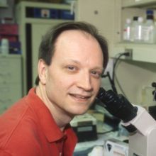 M. Mueckler looking at the camera in front of his microscope in 1998. 